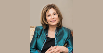 JoAnn Falletta posing for a portrait, smiling warmly. Image provided by the Omaha Symphony.