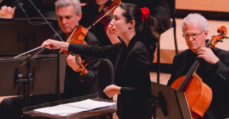 Serena Reuten, Assistant Conductor of the Omaha Symphony, conducting the orchestra during a performance.