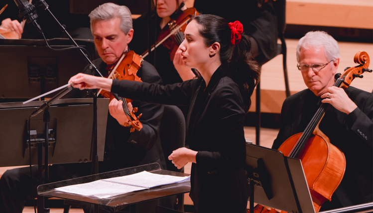 Serena Reuten, Assistant Conductor of the Omaha Symphony, conducting the orchestra during a performance.
