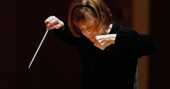 JoAnn Falletta conducting the Omaha Symphony, poised with baton in hand during a performance.
