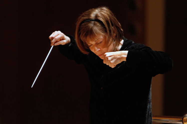 JoAnn Falletta conducting the Omaha Symphony, poised with baton in hand during a performance.