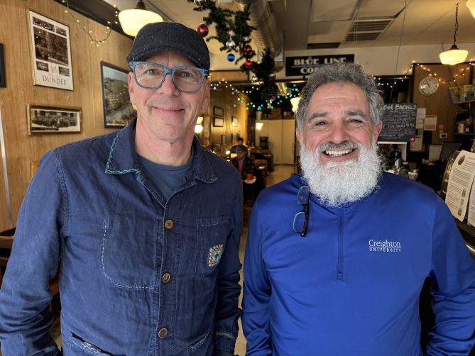 Jeff Koterba and Jack Phillips smiling at Blue Line Coffee in Dundee. The shop is decorated for Christmas.