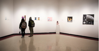 Two visitors observing artwork at the UNO Art Gallery.
