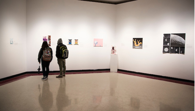 Two visitors observing artwork at the UNO Art Gallery.