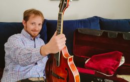 Ben leaning on a couch holding a guitar