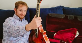 Ben leaning on a couch holding a guitar