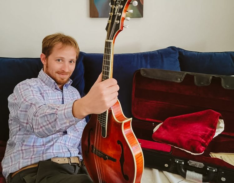 Ben leaning on a couch holding a guitar
