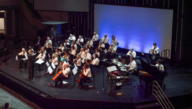 Members of the Intergeneration Orchestra of Omaha perform together on stage, blending youth and experience in a live concert.