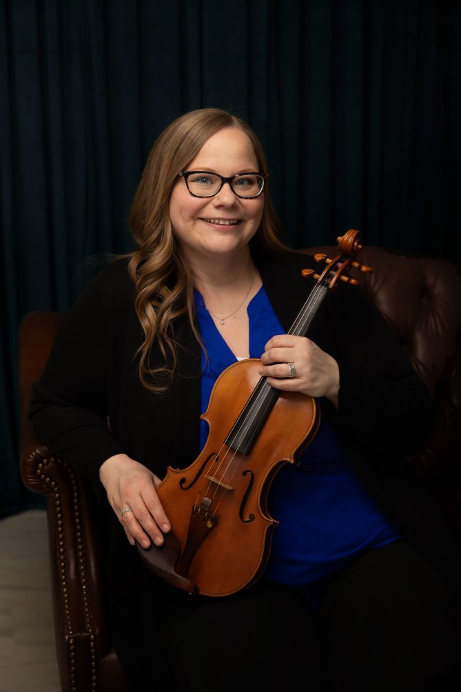 Rose Rydberg holding a violin and smiling. 