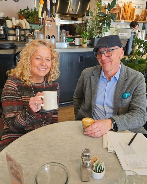 Jeff and Diane sitting at a table and holding coffees