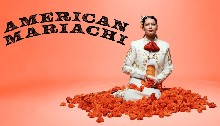 The character Lucha sits peacefully in a vibrant bed of flowers, surrounded by colorful blooms, with the text “American Mariachi” above her.