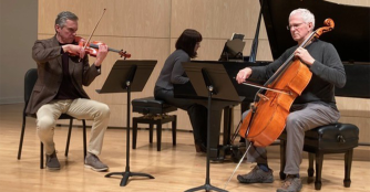 Three musicians from the Omaha Chamber Music Society perform in an intimate chamber setting, focused on strings.
