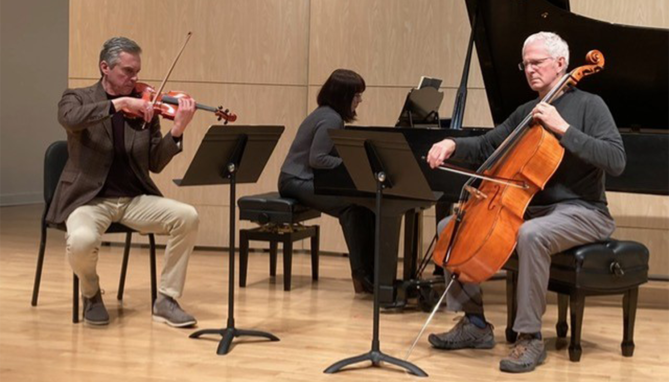 Three musicians from the Omaha Chamber Music Society perform in an intimate chamber setting, focused on strings.