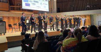 Jazz Camp performers pose on stage at UNO, dressed in coordinated outfits after their show.