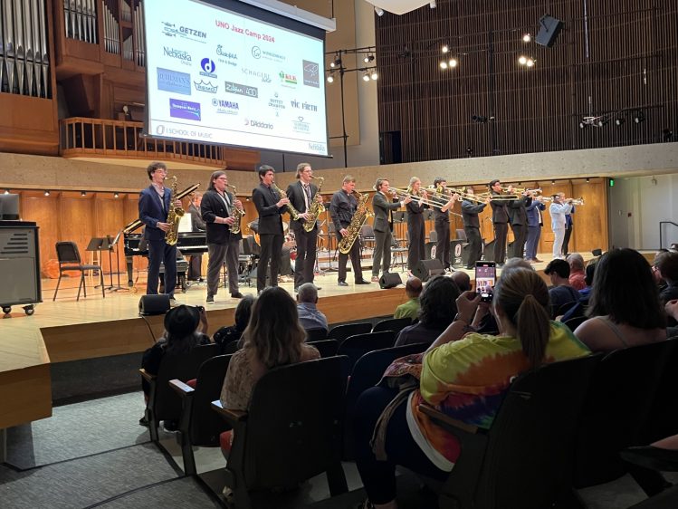 Jazz Camp performers pose on stage at UNO, dressed in coordinated outfits after their show.