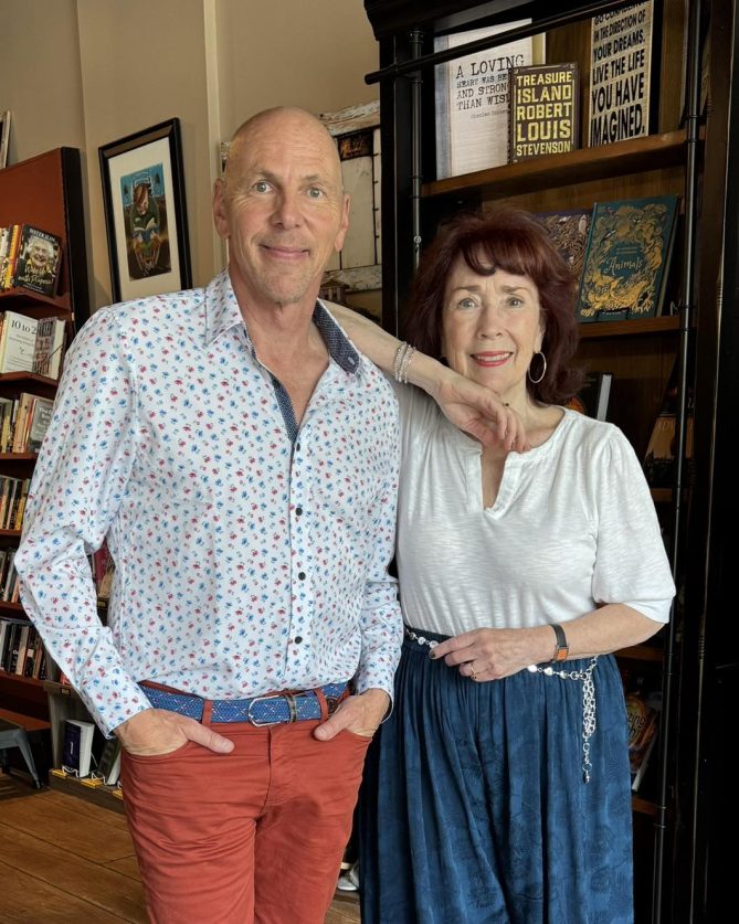 Jeff and Anne Marie standing together. Anne Marie has her arm on Jeff's shoulder. 