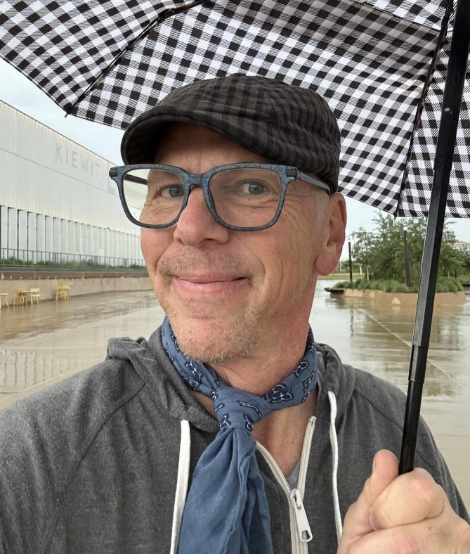 Selfie of Jeff holding an umbrella outside in the rain. 