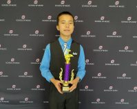 Bryan holding a trophy in front of a UNO banner
