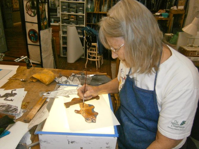 Julee Lowe at a light table woking on a stained glass window design in her studio 