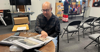 Photographer John Kubat stands beside his framed images at the opening of his exhibition, The Symphony Through the Lens.