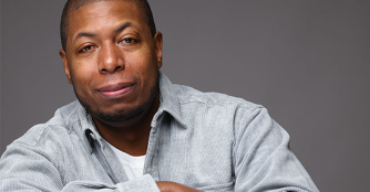 Dana Murray stands in front of NOMA with his arms crossed, smiling confidently.