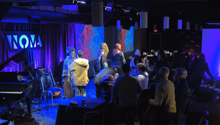 Interior of NOMA Café featuring cozy lighting, tables arranged for live jazz, and musicians performing on stage.