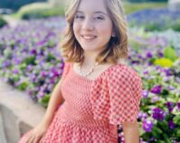 Marilyn LeClair, sitting outside in front of flowers.