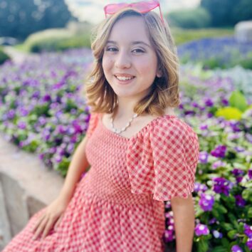 Marilyn LeClair, sitting outside in front of flowers.