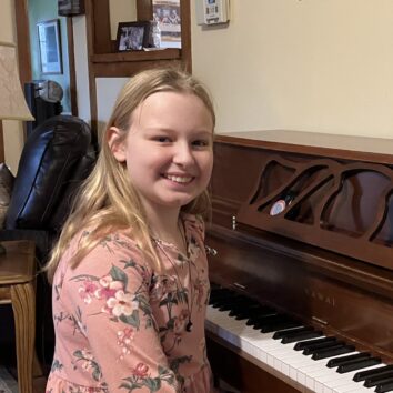 Maggie Dickinson smiling while sitting at a piano