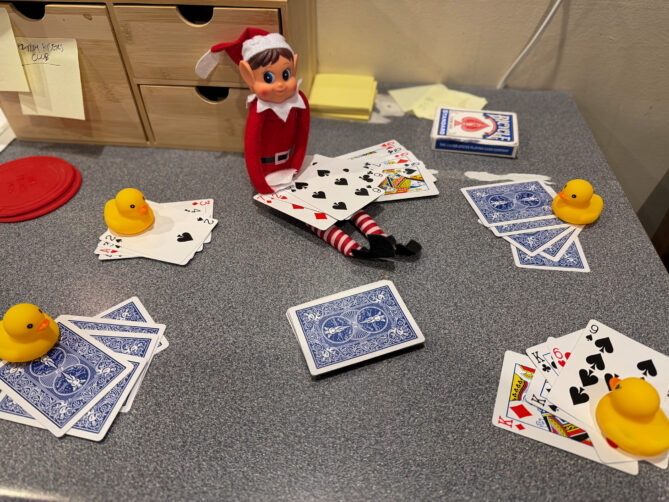Elf on the Shelf playing cards with four rubber ducks. Cards are everywhere. It's all very silly.