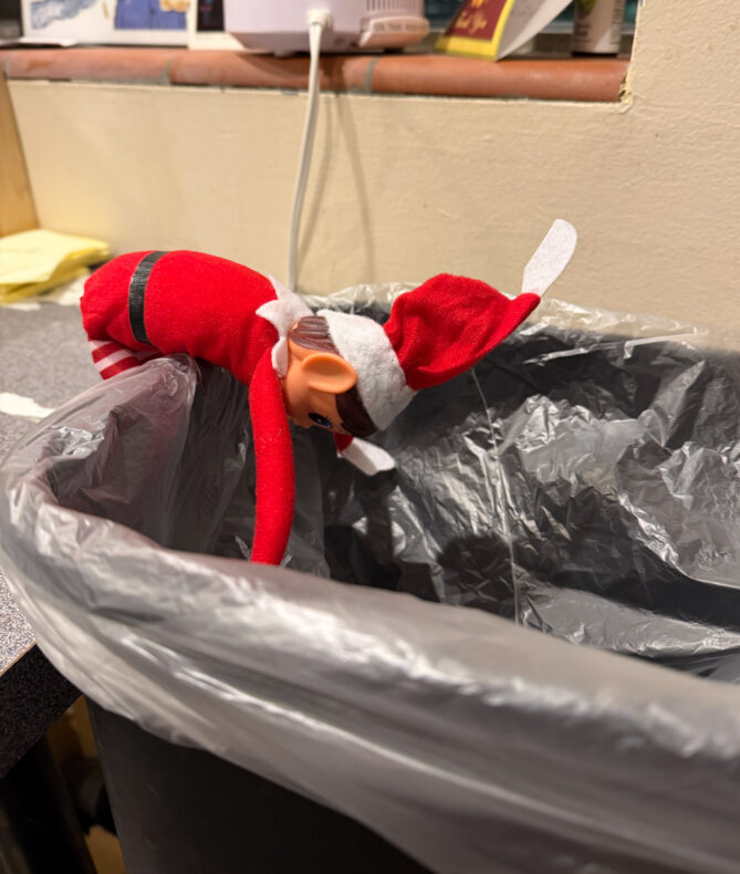 Elf on the shelf named Ivanoe with his head in the garbage can--the joke is that maybe he drank too much and how isn't feeling so well.
