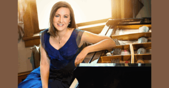 Local pianist Ann Madison stands beside her piano wearing an elegant dress, smiling warmly in a softly lit room.