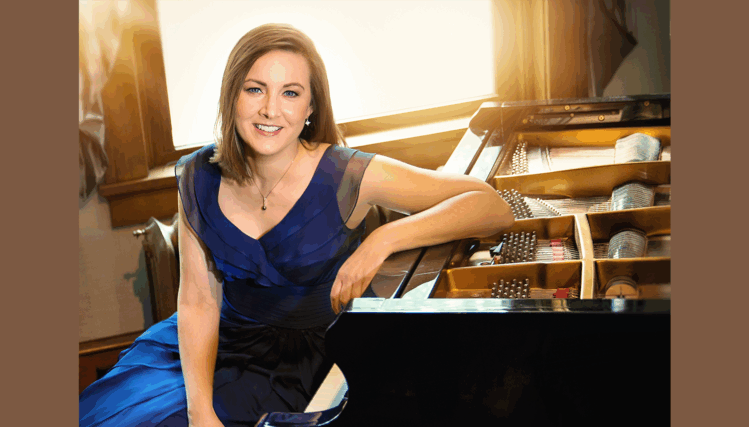 Local pianist Ann Madison stands beside her piano wearing an elegant dress, smiling warmly in a softly lit room.