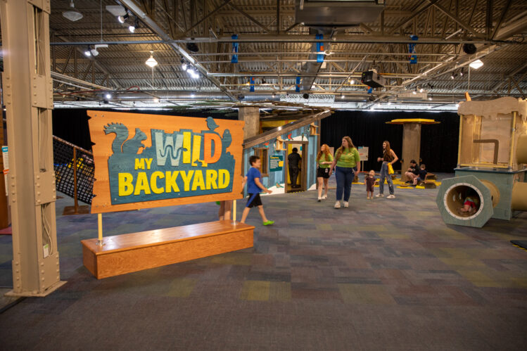 Children and museum staff explore interactive nature displays inside the Omaha Children’s Museum exhibition “My Wild Backyard.”