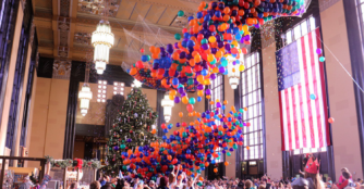Colorful balloons fall from the ceiling as children and adults reach up to catch them during the Durham Museum’s Noon Year’s Eve celebration.