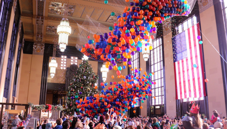 Colorful balloons fall from the ceiling as children and adults reach up to catch them during the Durham Museum’s Noon Year’s Eve celebration.