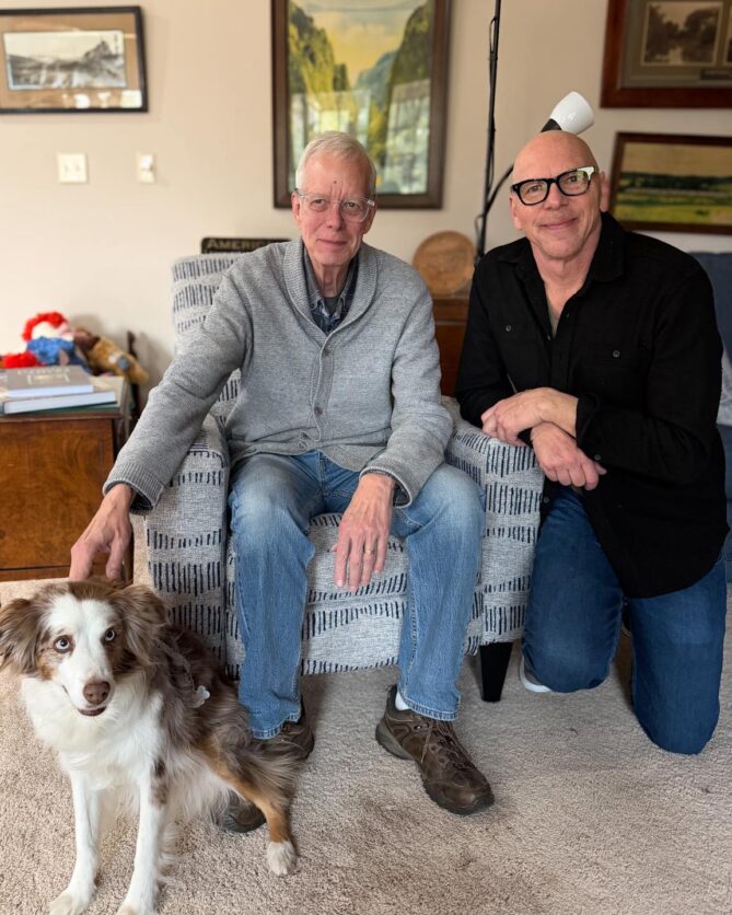 Jeff Koterba kneeling next to Charlie Duckworth and his Australian Shepherd, Zoe. 