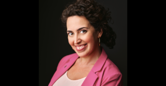 Portrait of Meghann Henry, Executive Director of the Omaha Conservatory of Music, smiling and seated in a bright music studio. Image provided by Meghann Henry.