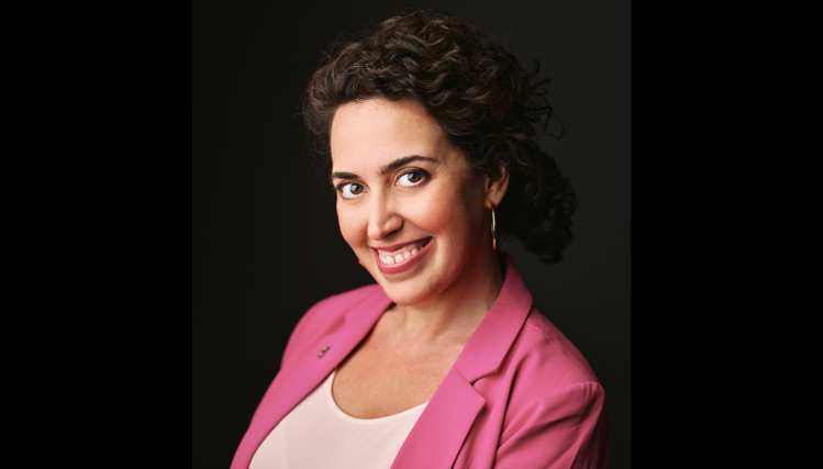 Portrait of Meghann Henry, Executive Director of the Omaha Conservatory of Music, smiling and seated in a bright music studio. Image provided by Meghann Henry.