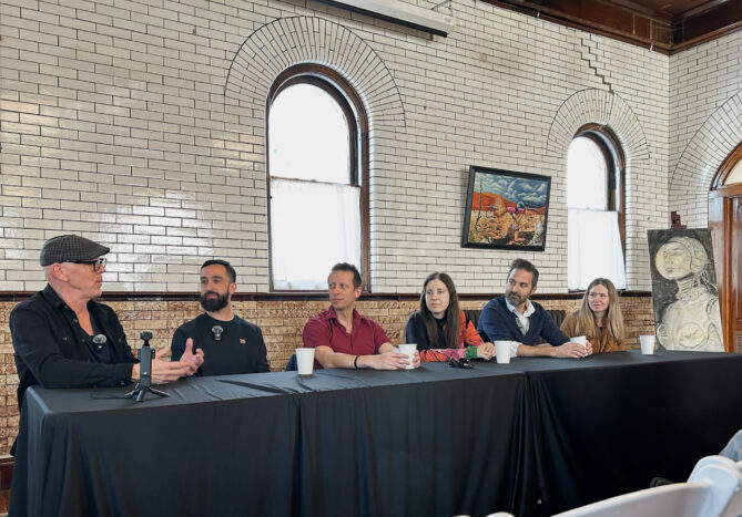 Jeff Koterba leading a panel discussion on learning French and other languages at Omaha's Joslyn Castle Carriage House on Saturday, February 21st. The photo shows Koterba along with five panelists and also a character in a painting off to the side seemingly also listening in. 