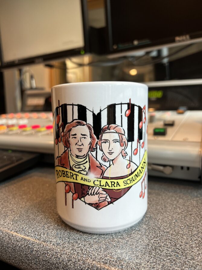 Robert and Clara Schumann mug designed by Jeff Koterba. White mug with a red design.