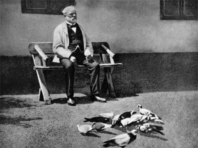 Czech composer, Antonín Dvořák siting on a bench and with his pigeons 