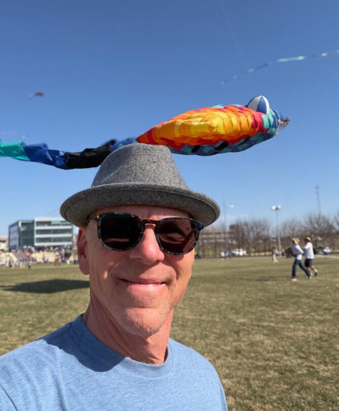 Picture of Jeff in a park with a big balloon behind him floating in the sky