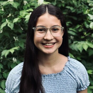 Azalea Armenariz smiles in front of a wall of plants.