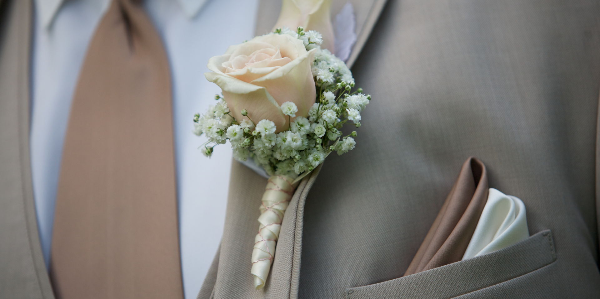 A close up picture of a flower pin on a suit